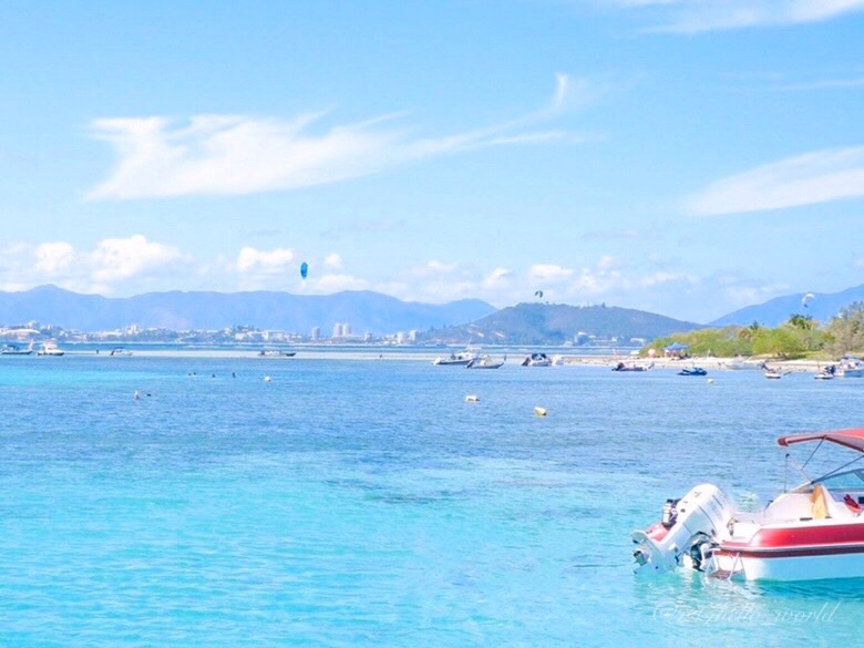 Emerald-green lagoon and boats seen from Ilot Maitre, with Noumea in the distance