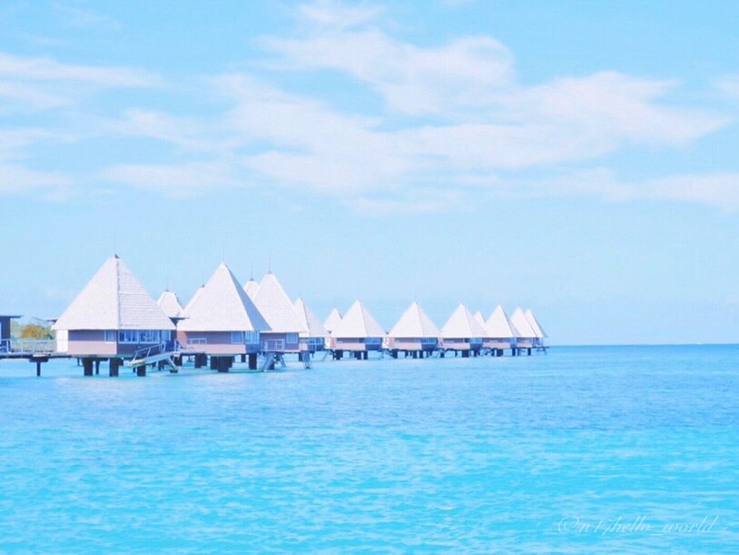 Overwater bungalows lined up over the blue lagoon at Ilot Maitre